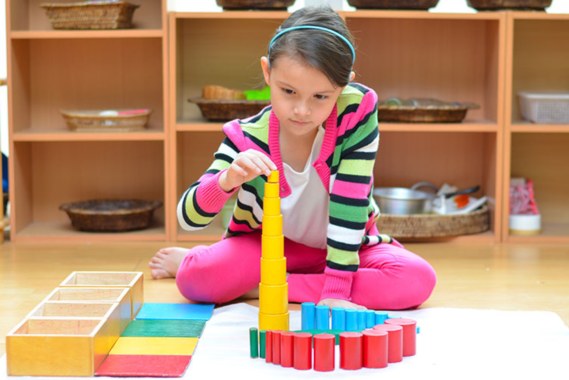 Petite fille qui réalise une activité Montessori avec des éléments en bois