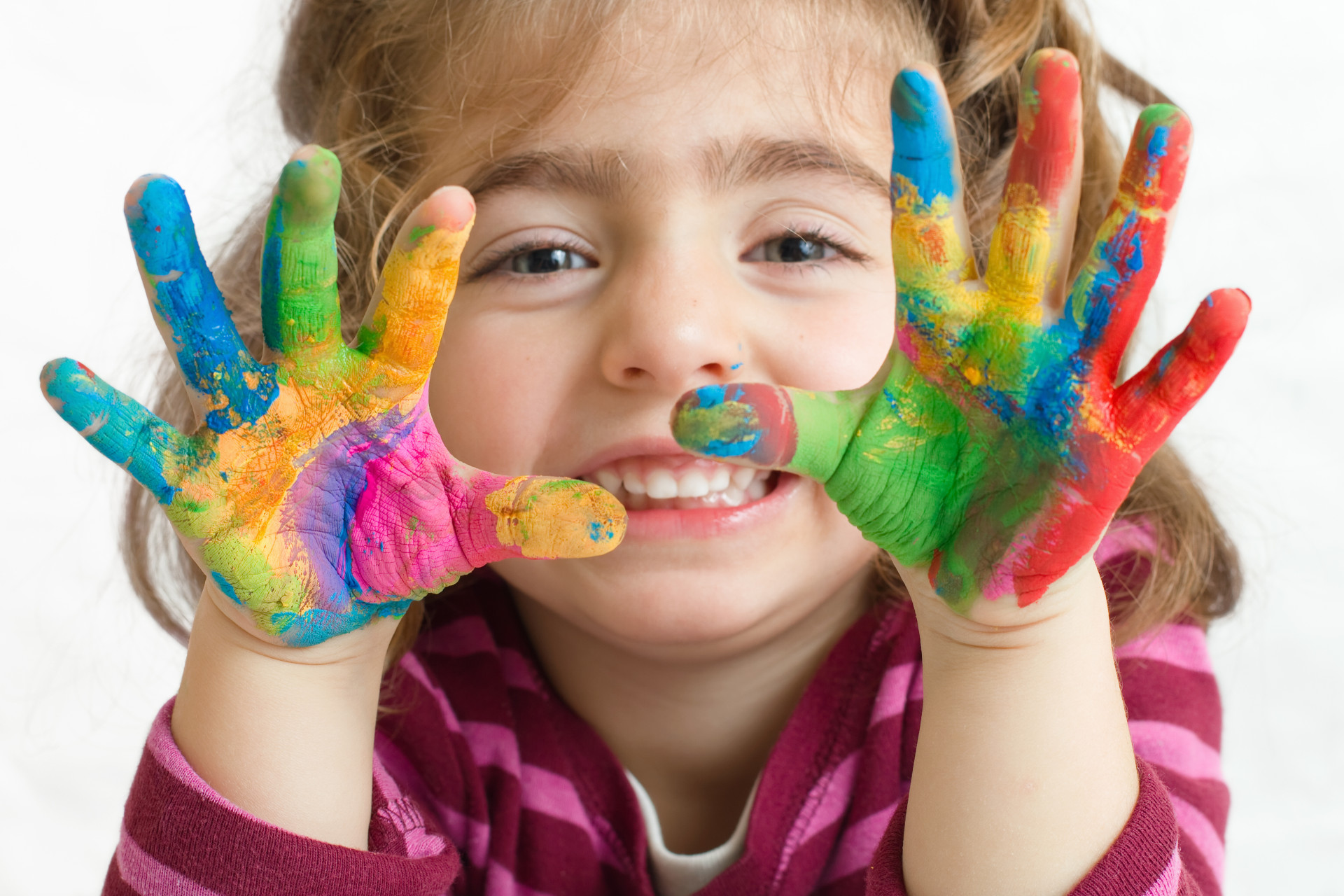 Petite fille souriante avec les mains pleines de peinture. 