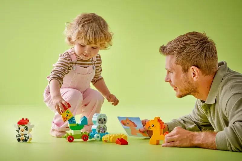 Petite fille qui joue au train des animaux de Lego Duplo