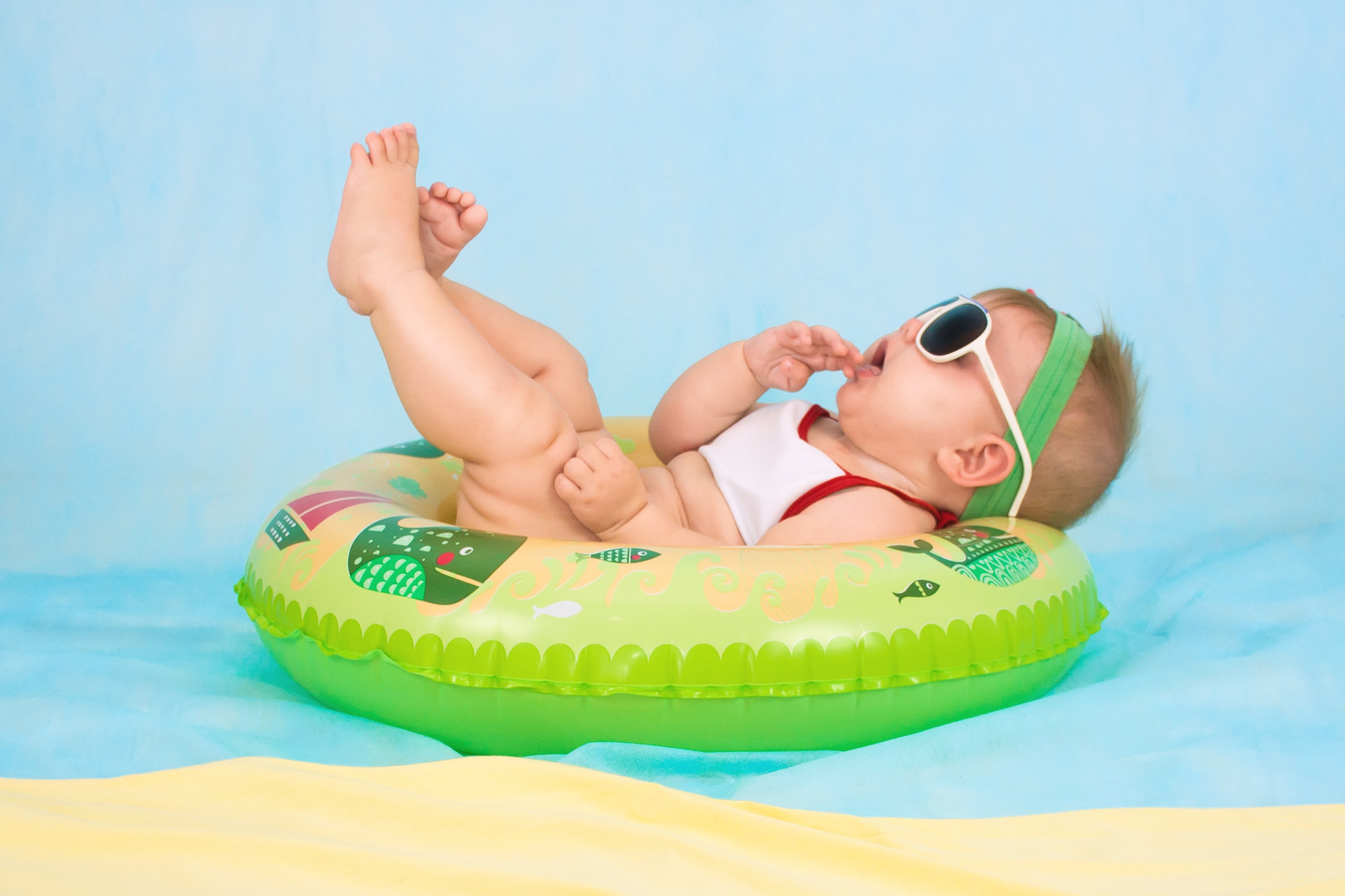 Bébé couché sur une bouée avec ses lunettes de soleil