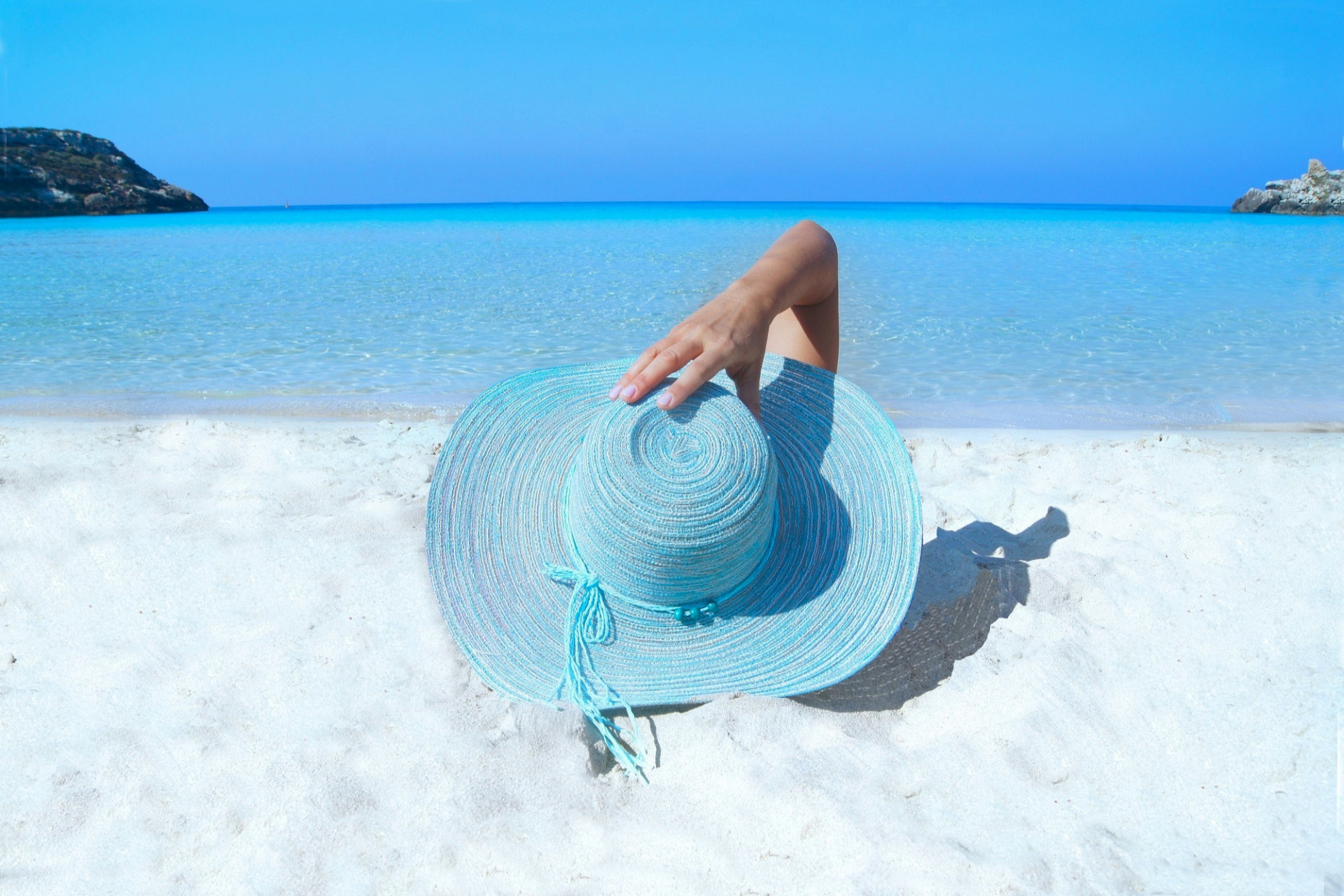 Femme sur la plage avec un chapeau bleu