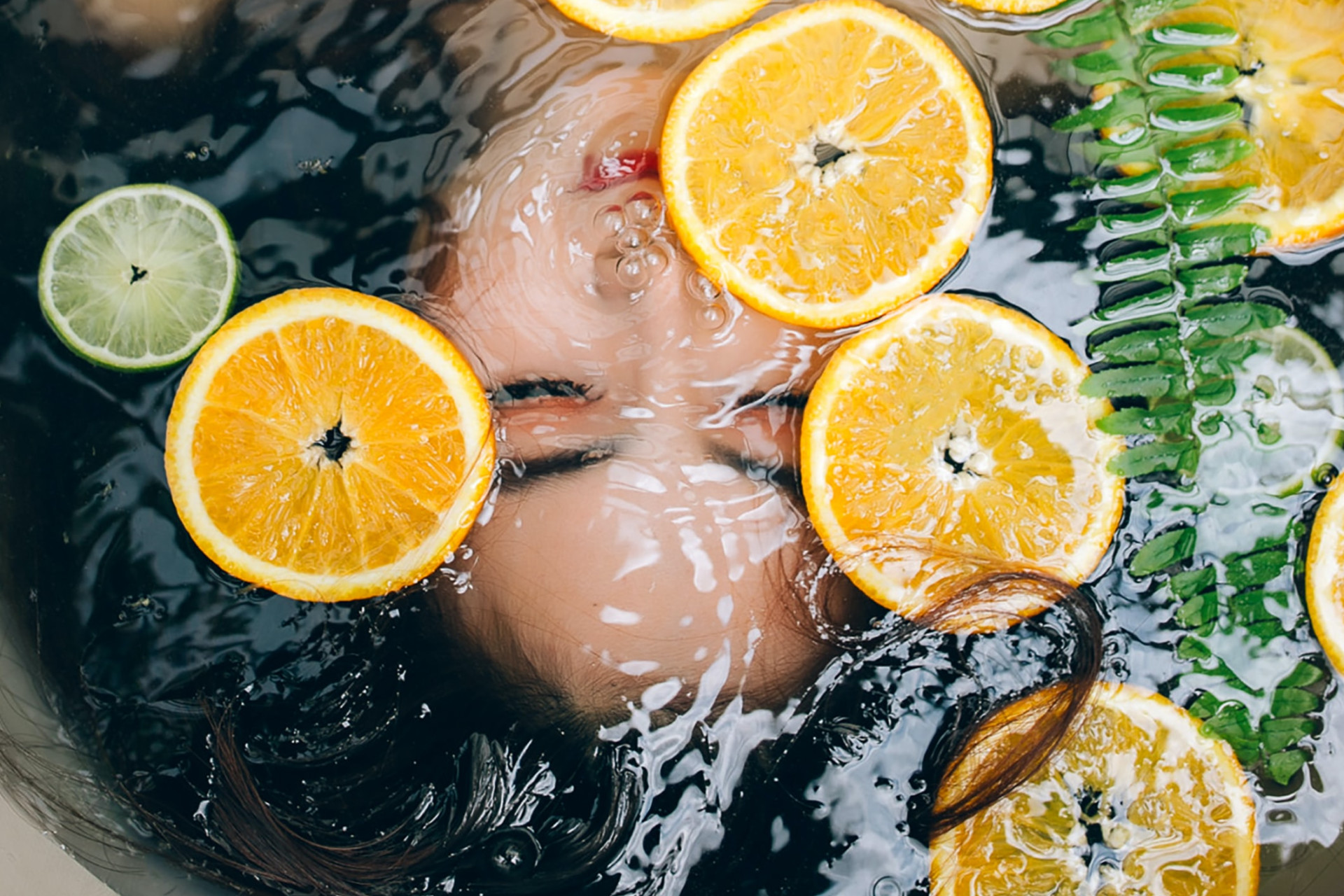 Femme sous l'eau de son bain avec des oranges