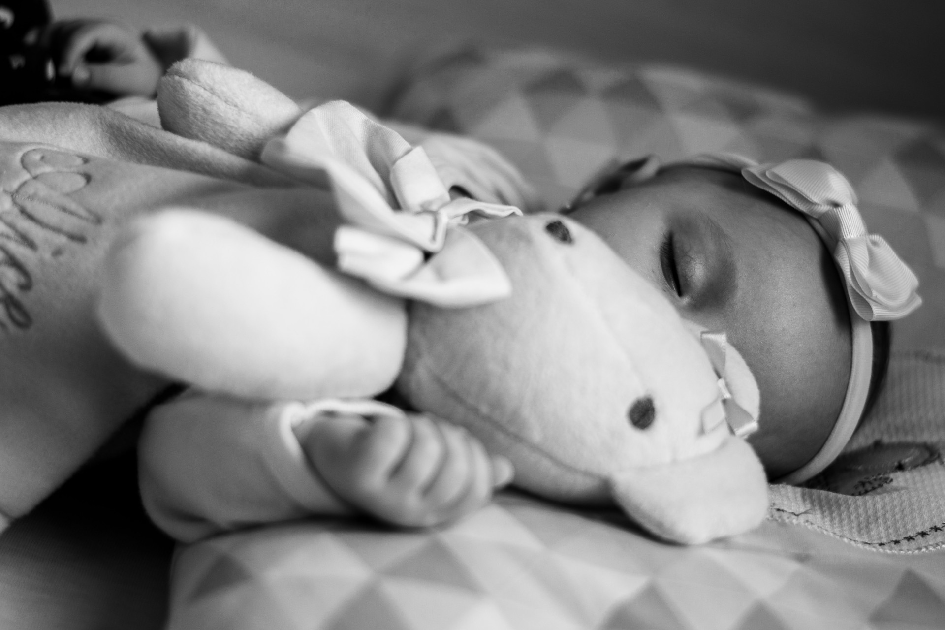 Photo en noir et blanc d'un bébé avec son doudou 