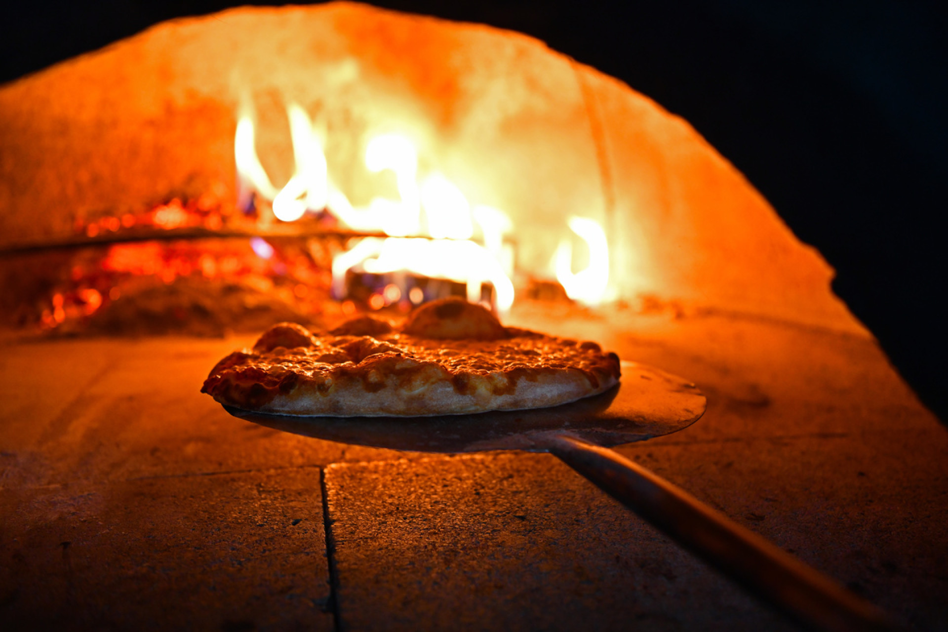 Pizza qui sort d'un four traditionnel au feu de bois