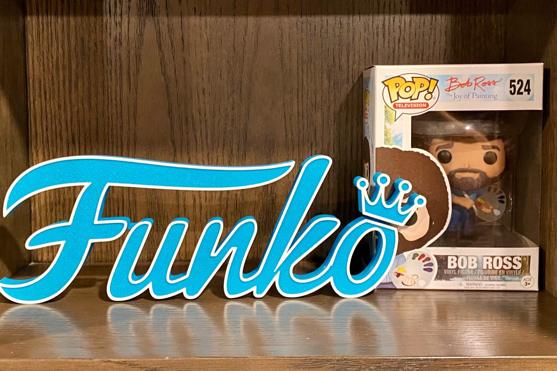 Logo de la marque Funko en bleu sur une étagère en bois.
