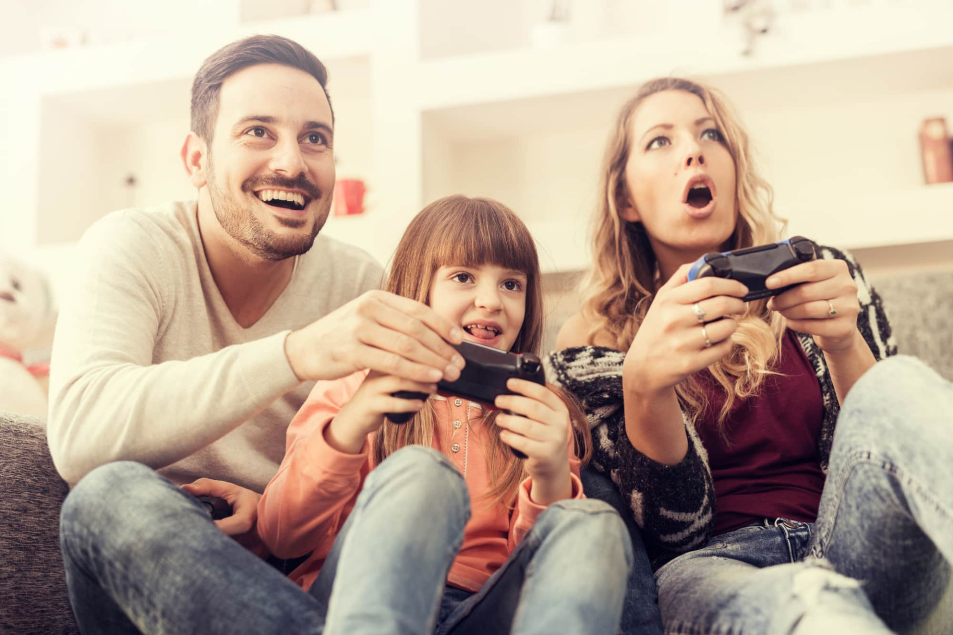 Une famille joue aux jeux vidéo sur une console dans leur salon.