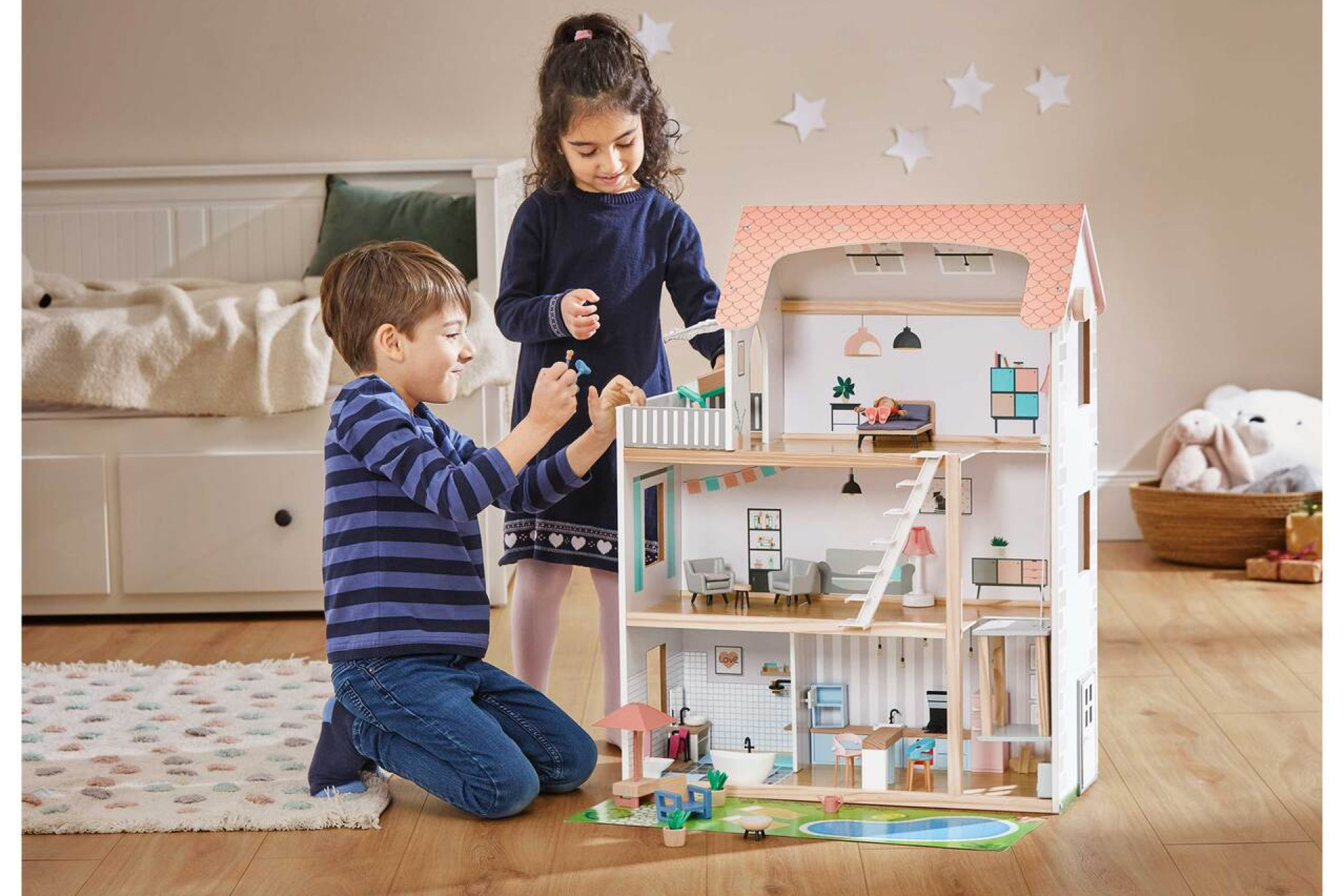 Un garçon et une fille qui jouent avec une maison de poupée