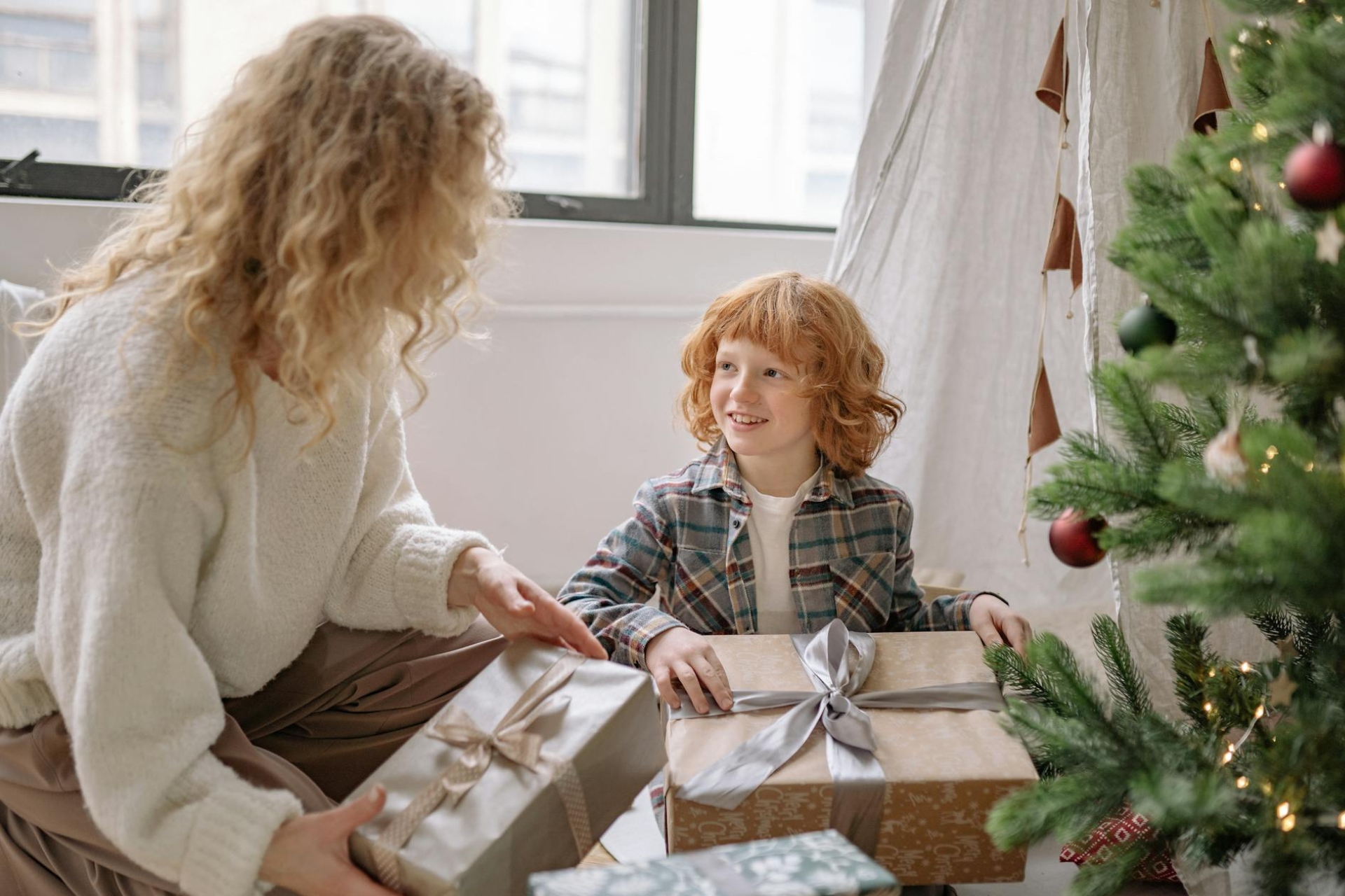 Un petit garçon et sa maman qui ouvrent les cadeaux de Noël