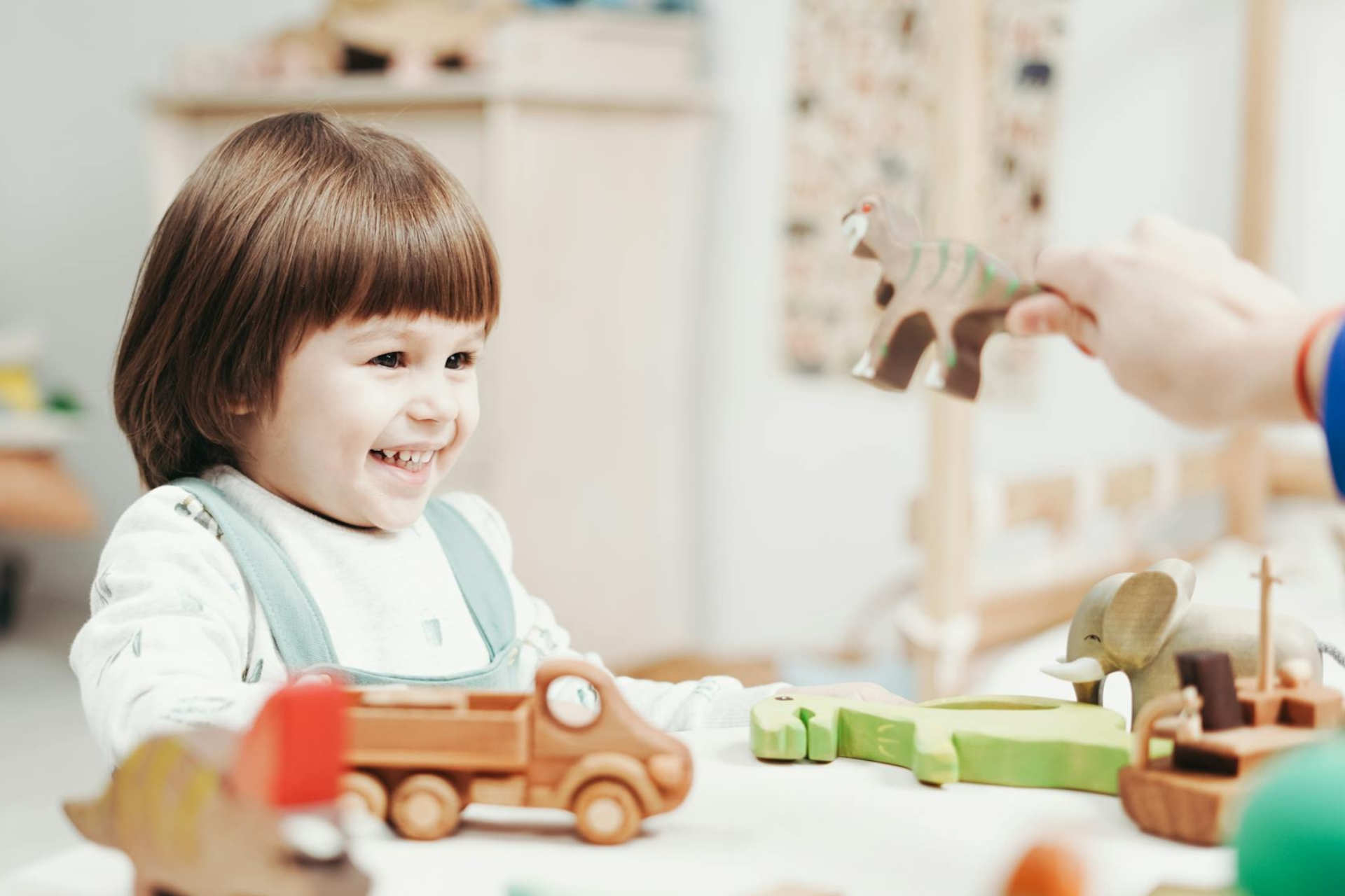 petit enfant avec des jouets dinosaures en bois