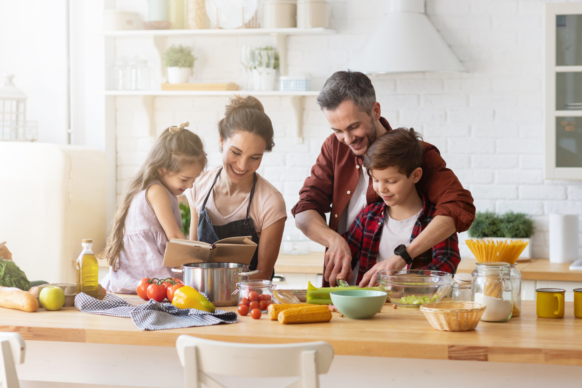 Un couple et ses deux enfants qui cuisinent dans la bonne humeur