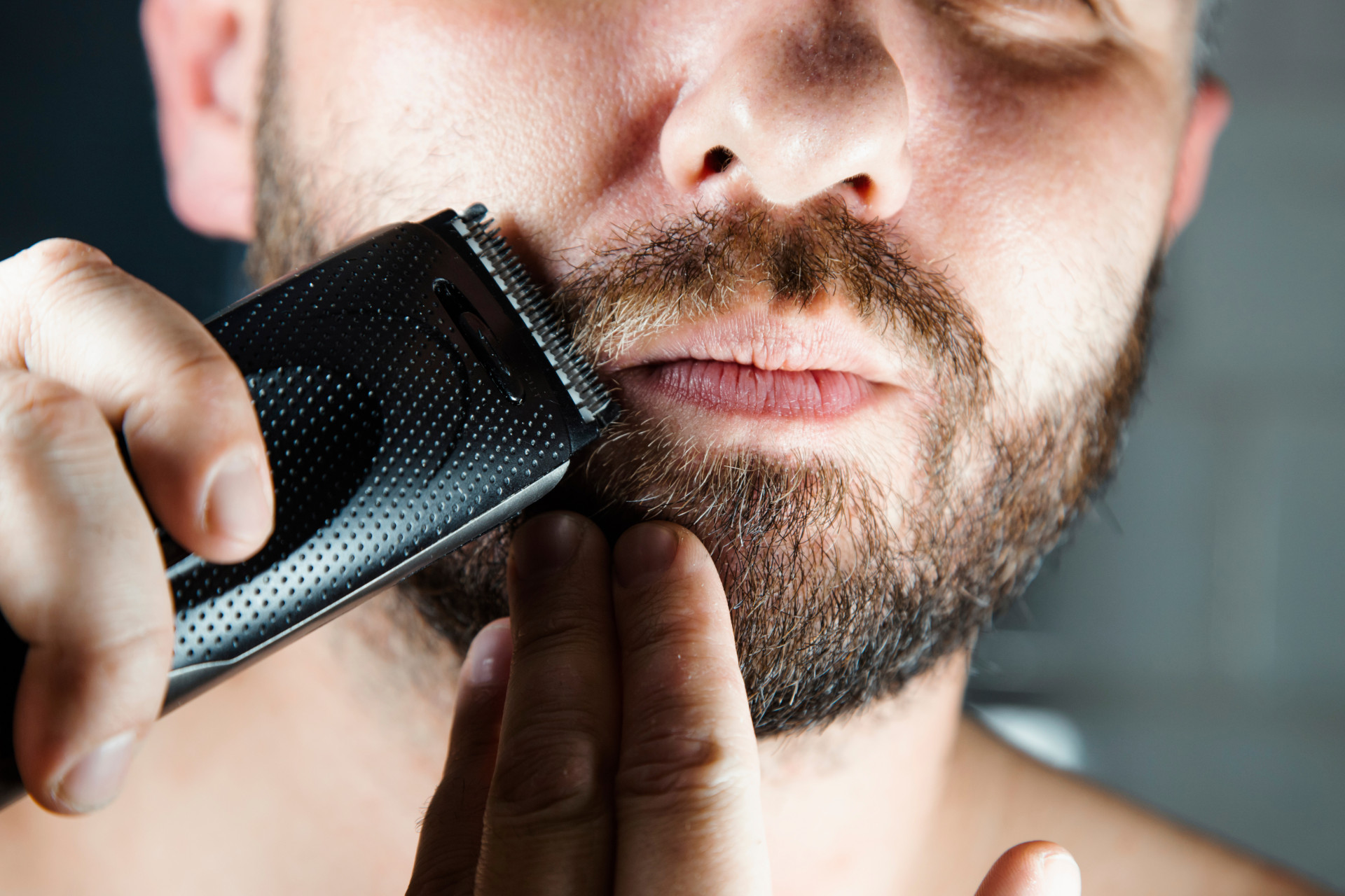 Un homme se taille la barbe avec une tondeuse à barbe